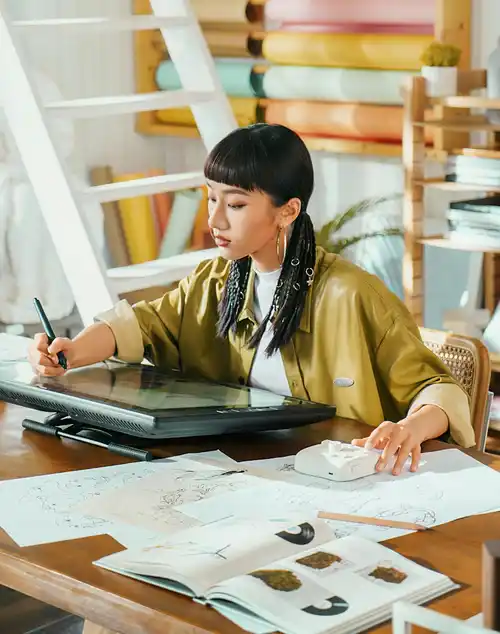 A designer drawing on a pen display in a bright studio